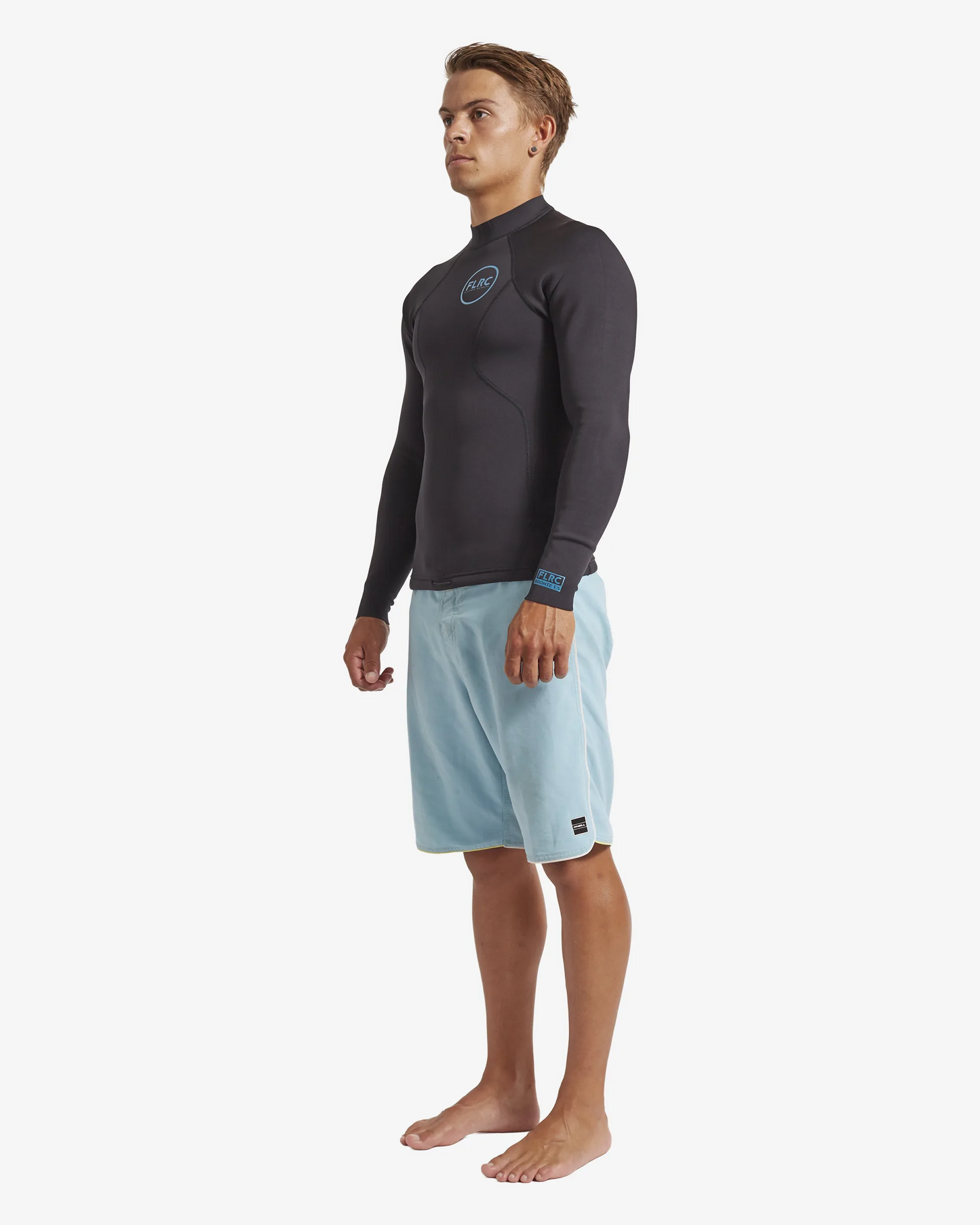 Man wearing black FLRC 1.5mm wetsuit top with blue logo, angled view in studio.