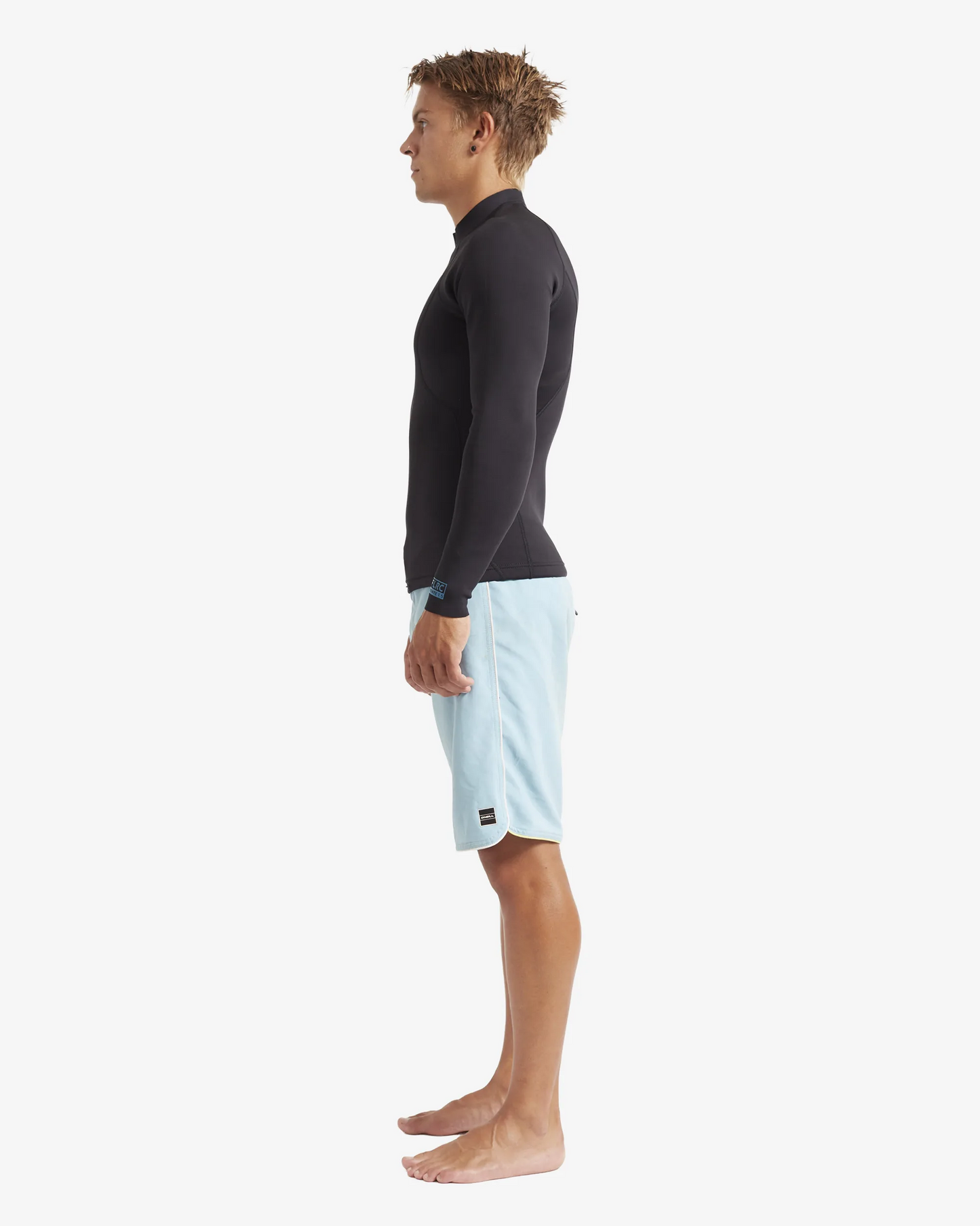 Man wearing black FLRC 1.5mm wetsuit top with blue logo, side view in studio.