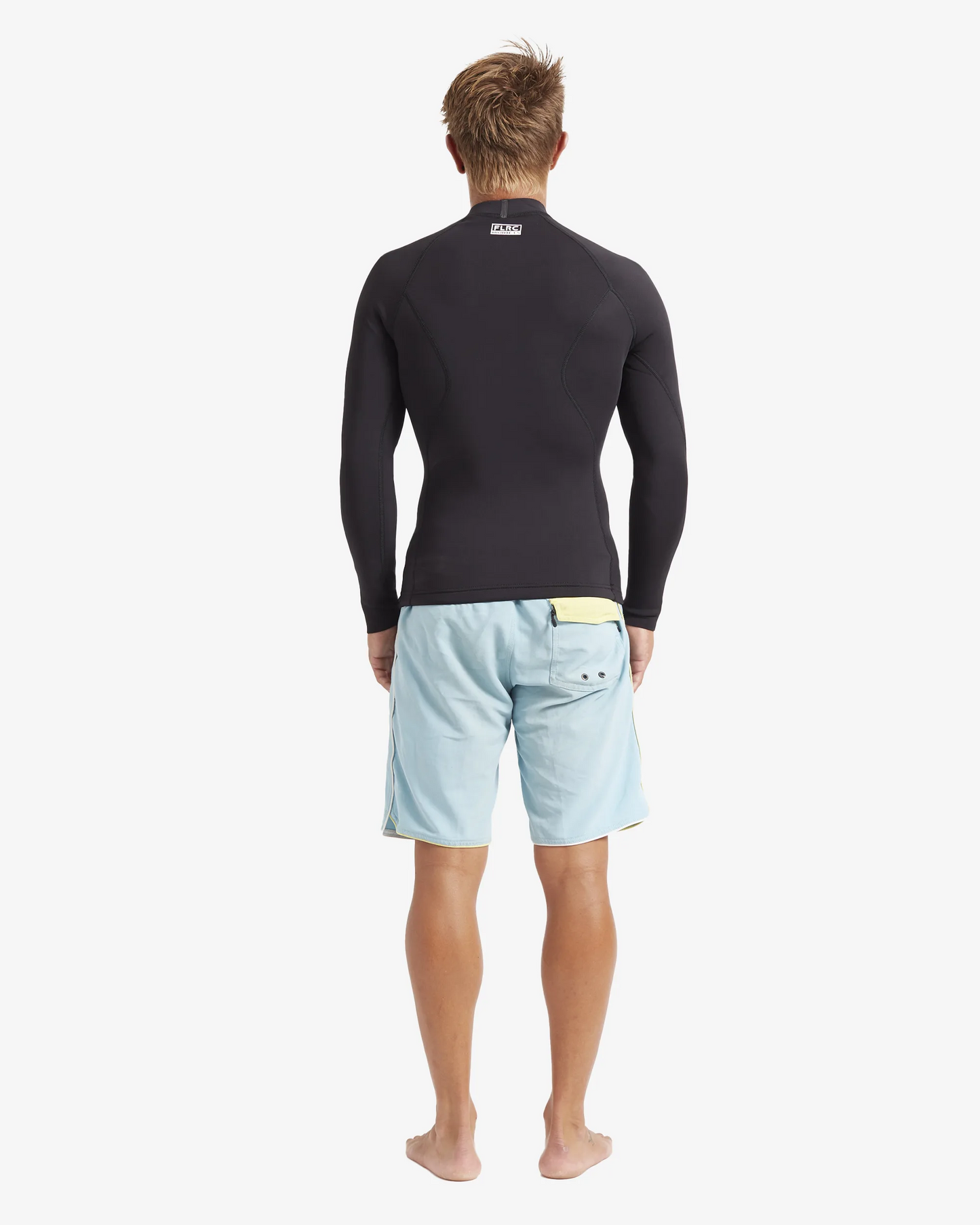 Man wearing black FLRC 1.5mm wetsuit top with white logo, back view in studio.