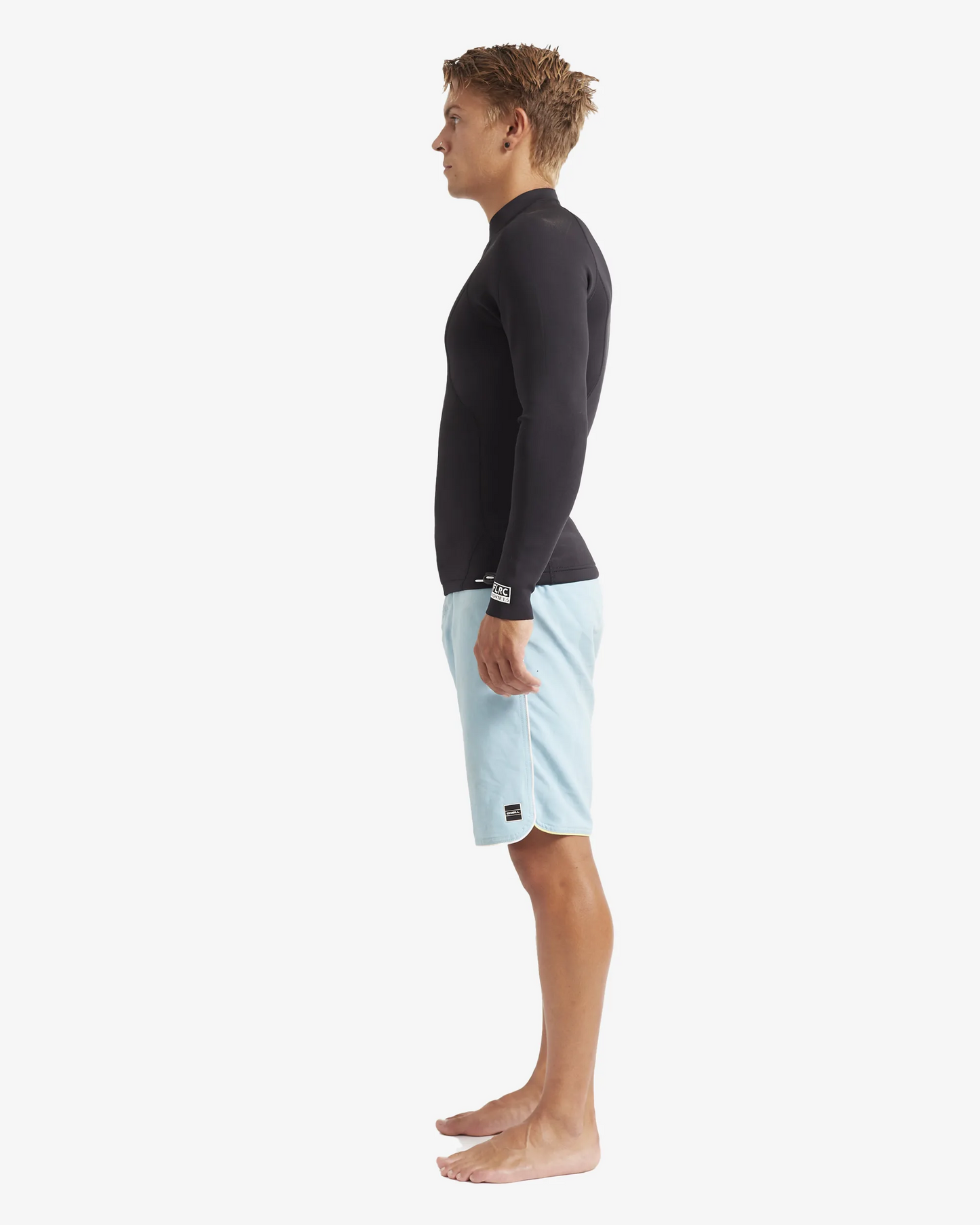 Man wearing black FLRC 1.5mm wetsuit top with white logo, side view in studio.