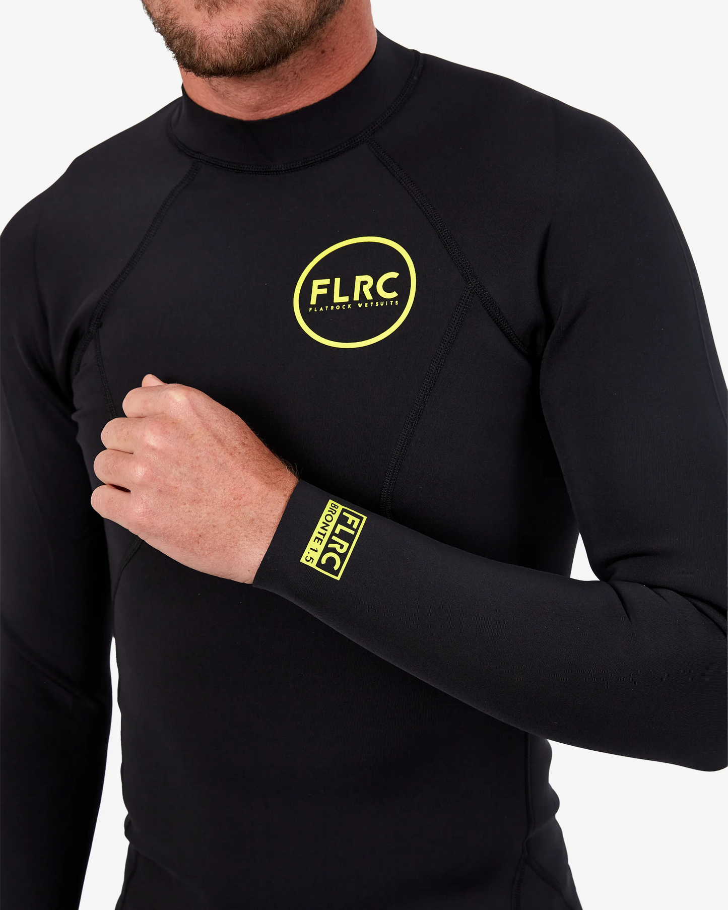 Extreme close-up of yellow FLRC logo and fine stitching detail on black 1.5mm wetsuit top.