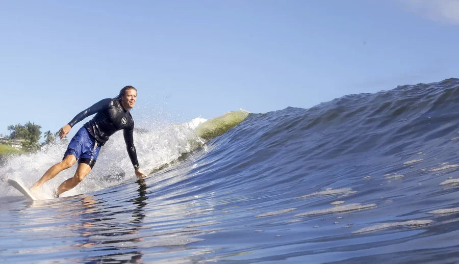 Surfer riding along the face of a small wave in the Men's 1.5mm Wetsuit Top V1