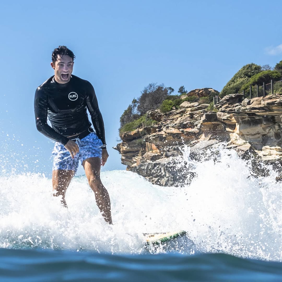 Surfer stretching shoulders on beach before paddling out to prevent rotator cuff injury