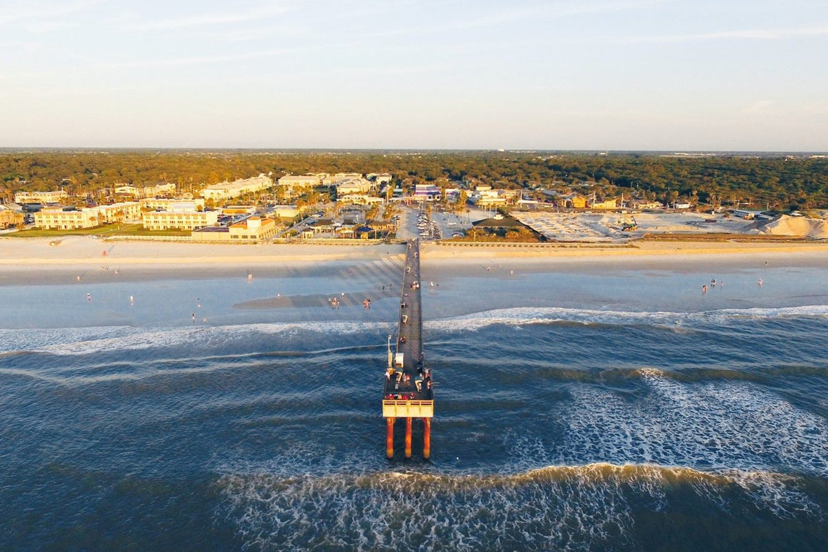 Aerial view of St. Augustine Beach Pier in Florida at sunset with surf lines either side