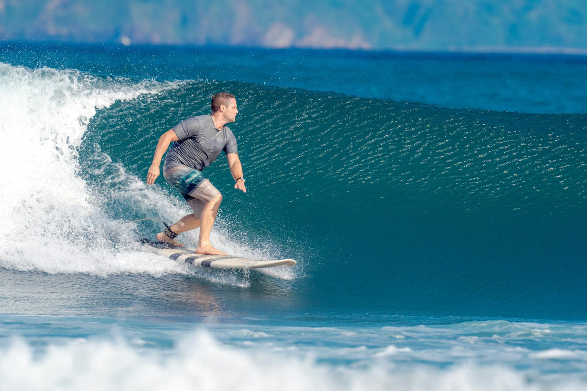 Surfer in a long-sleeve top and boardshorts riding a summer wave