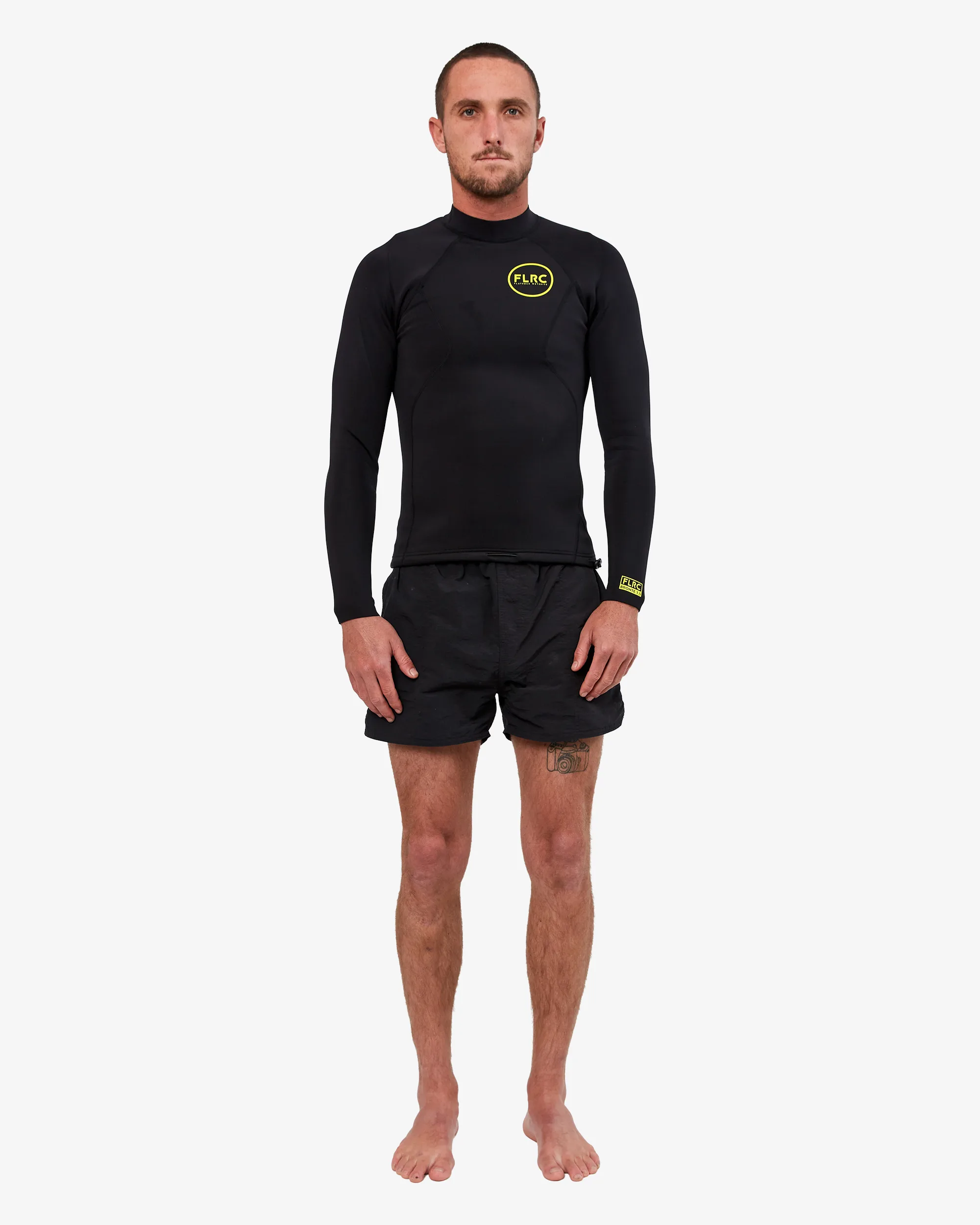 Man wearing black FLRC 1.5mm wetsuit top with yellow logo, front view in studio.