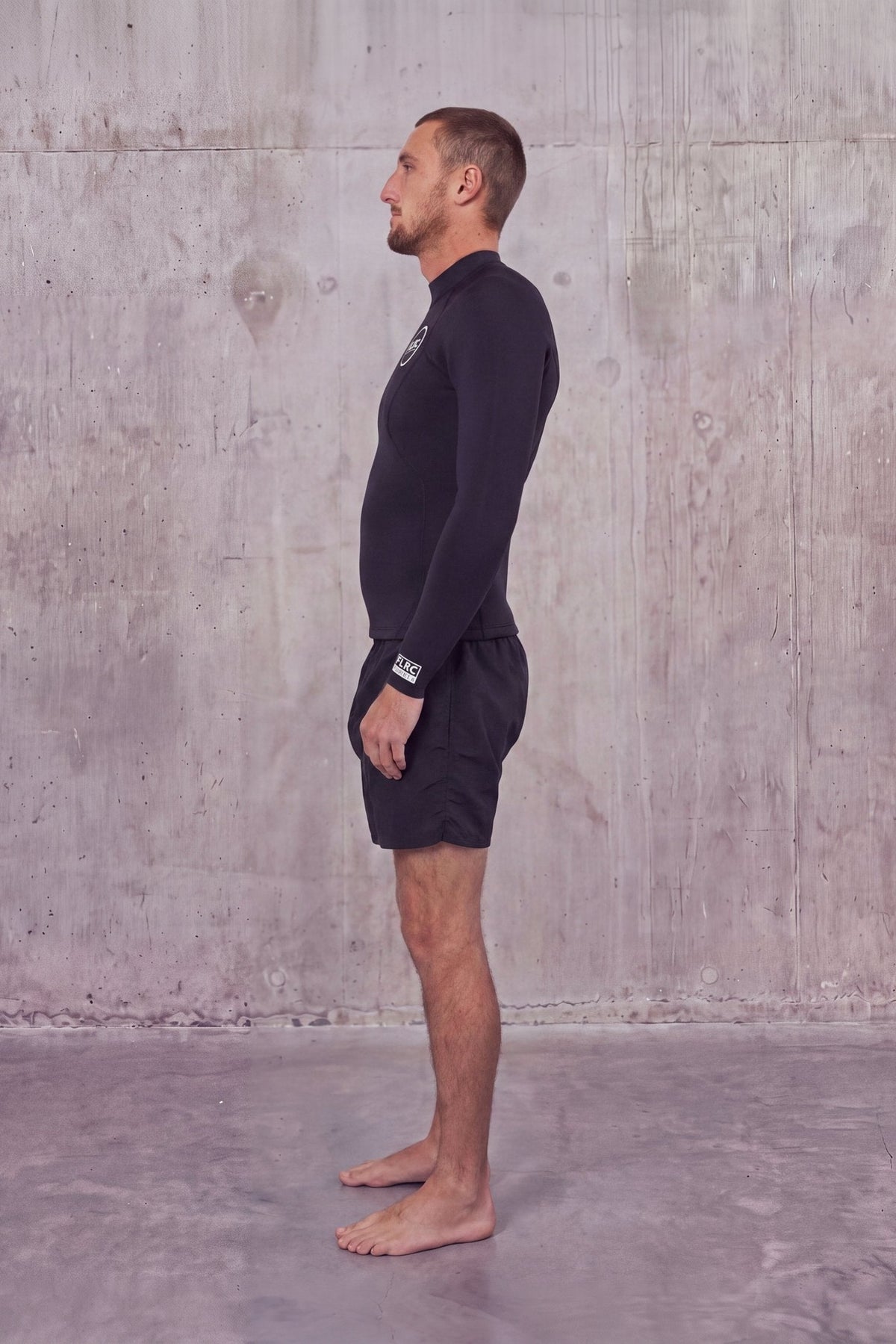 Side view of a man in the Men's 1.5mm Wetsuit Top V1, long sleeves and high neck