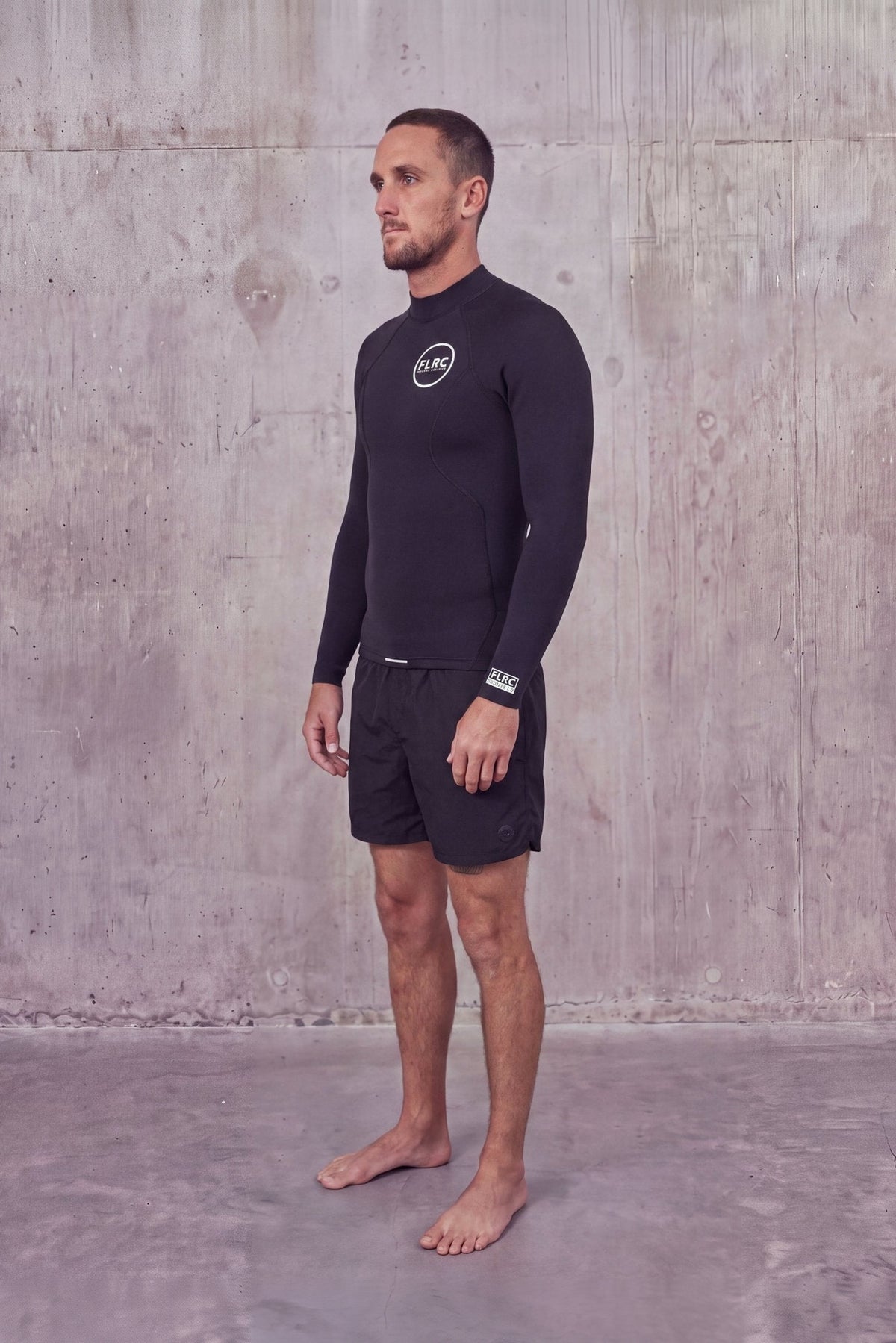 Man in Men's 1.5mm Wetsuit Top V1, three-quarter view showing the FLRC chest logo and sleeve label