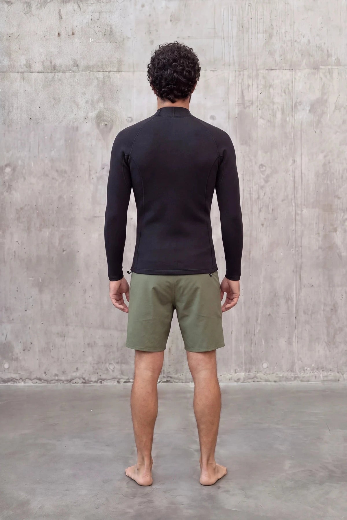 Back view of a man in the Men's 1.5mm Wetsuit Top V2 wetsuit top against a concrete wall