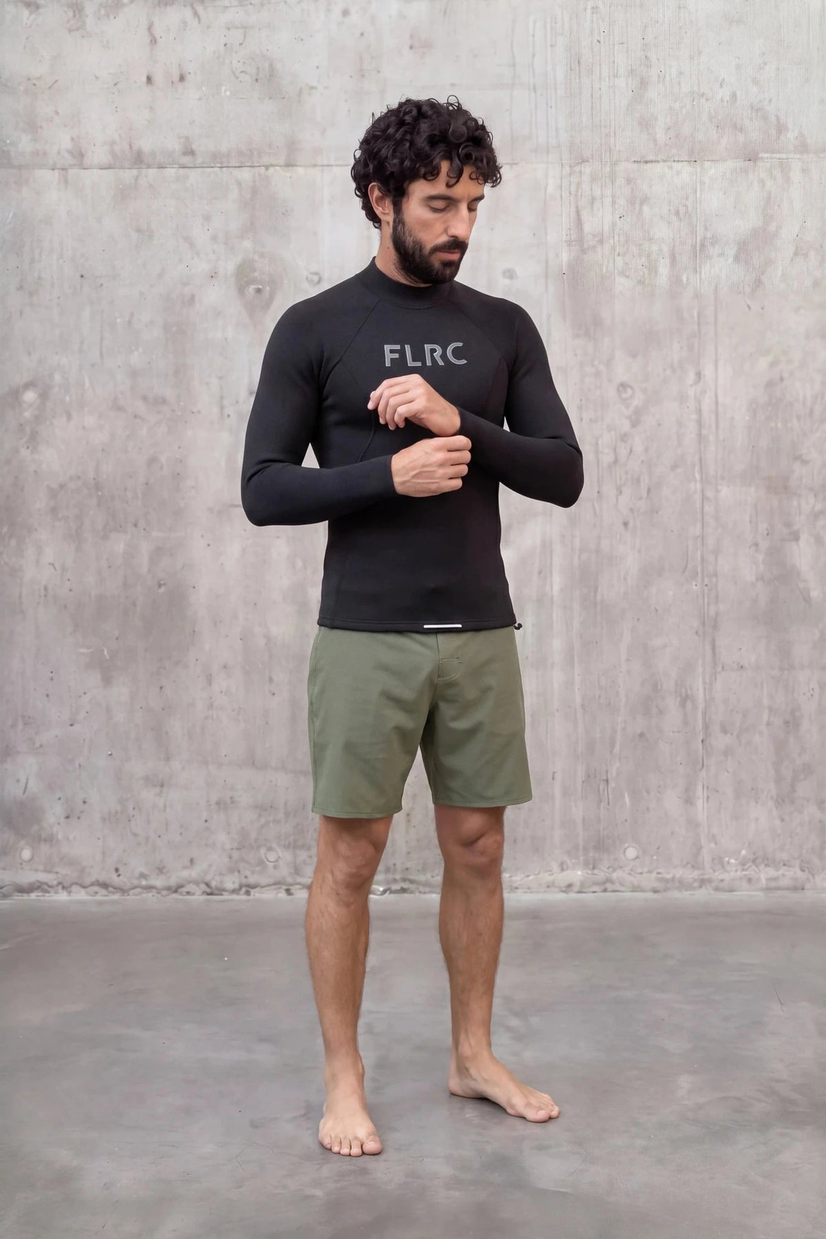 Man adjusting the cuff of the Men's 1.5mm Wetsuit Top V2, front view showing the FLRC chest logo