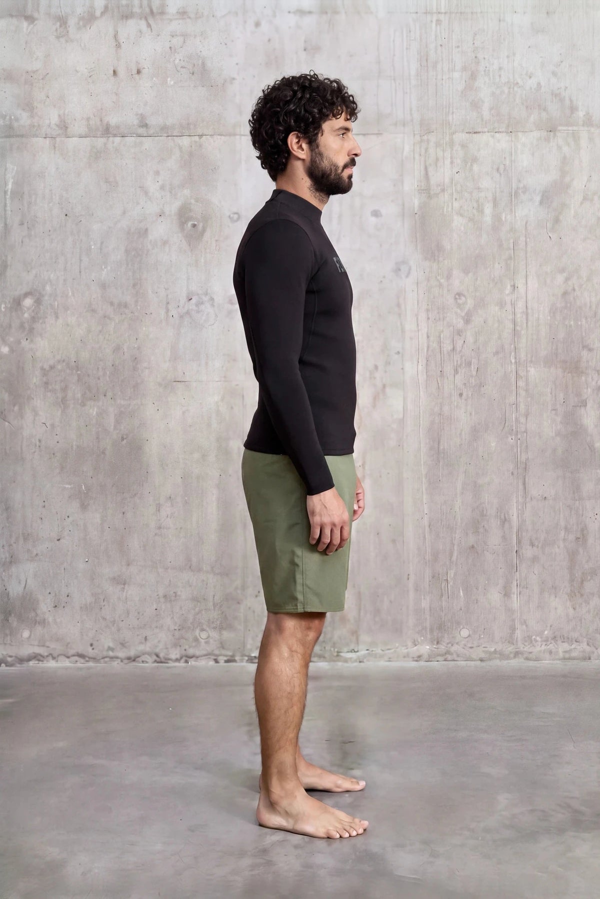 Side view of a man in the Men's 1.5mm Wetsuit Top V2, long sleeves and high neck