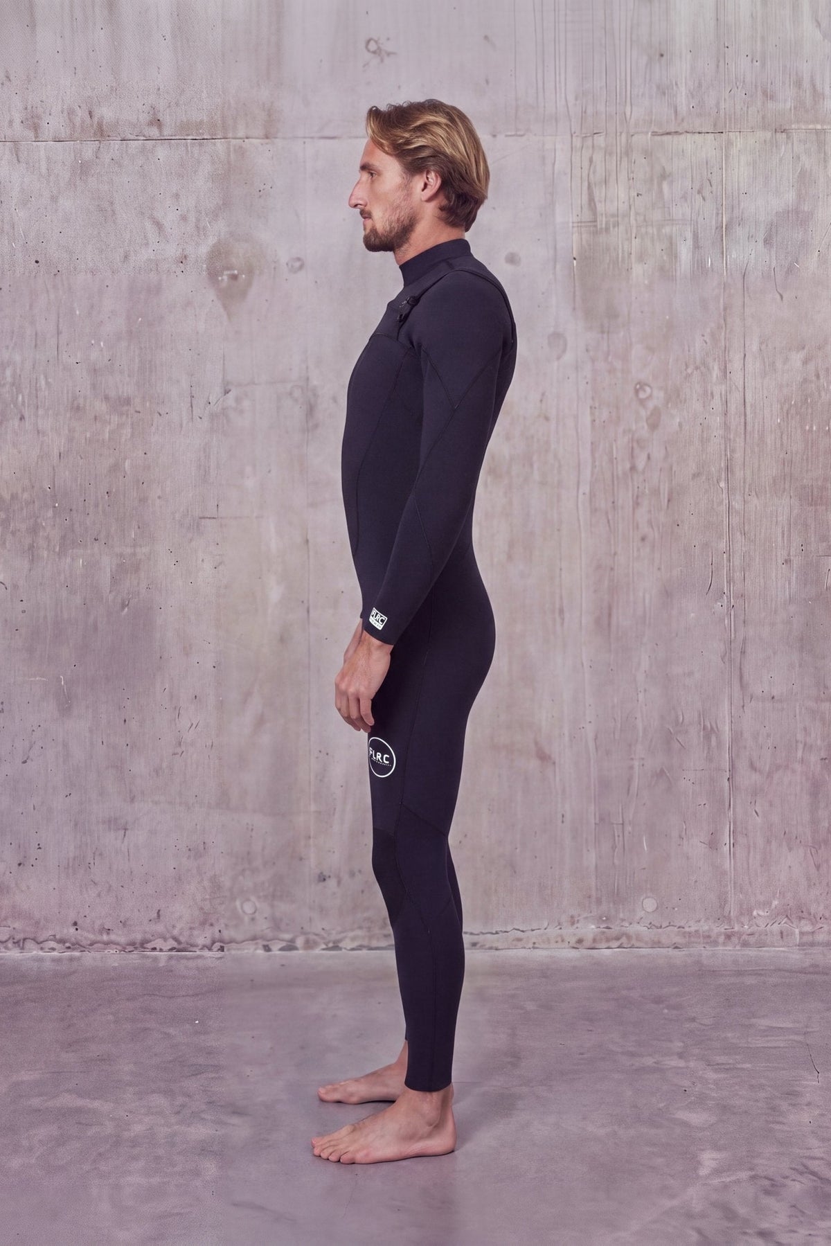 Side view of a man in the Men's 3/2mm Fullsuit V2 wetsuit with FLRC logo on the thigh