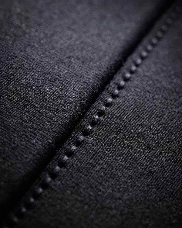Close-up of a blindstitched seam on the steamer, the stitch line running alongside the bonded panel join in the neoprene's jersey knit face